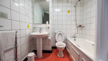 A bathroom with white tiled walls, a sink, a toilet, and a bathtub.