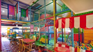 An indoor play area with netted climbing structures, a ball pit, and tables with chairs. - Bridge Inn by Greene King Inns (Bristol)