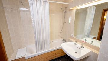 A bathroom with a bathtub, a shower, a sink, and a mirror.