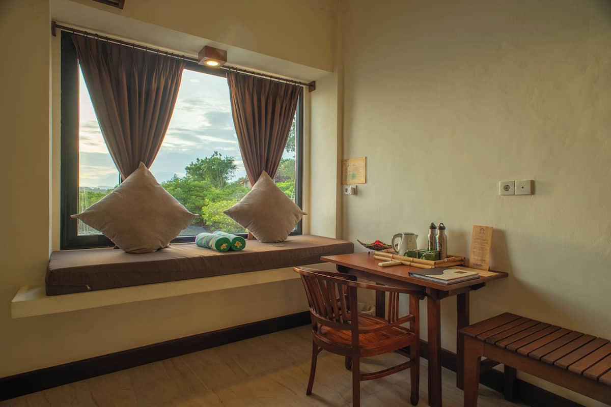 Una habitación con asiento junto a la ventana, una mesa con una silla y un banco.