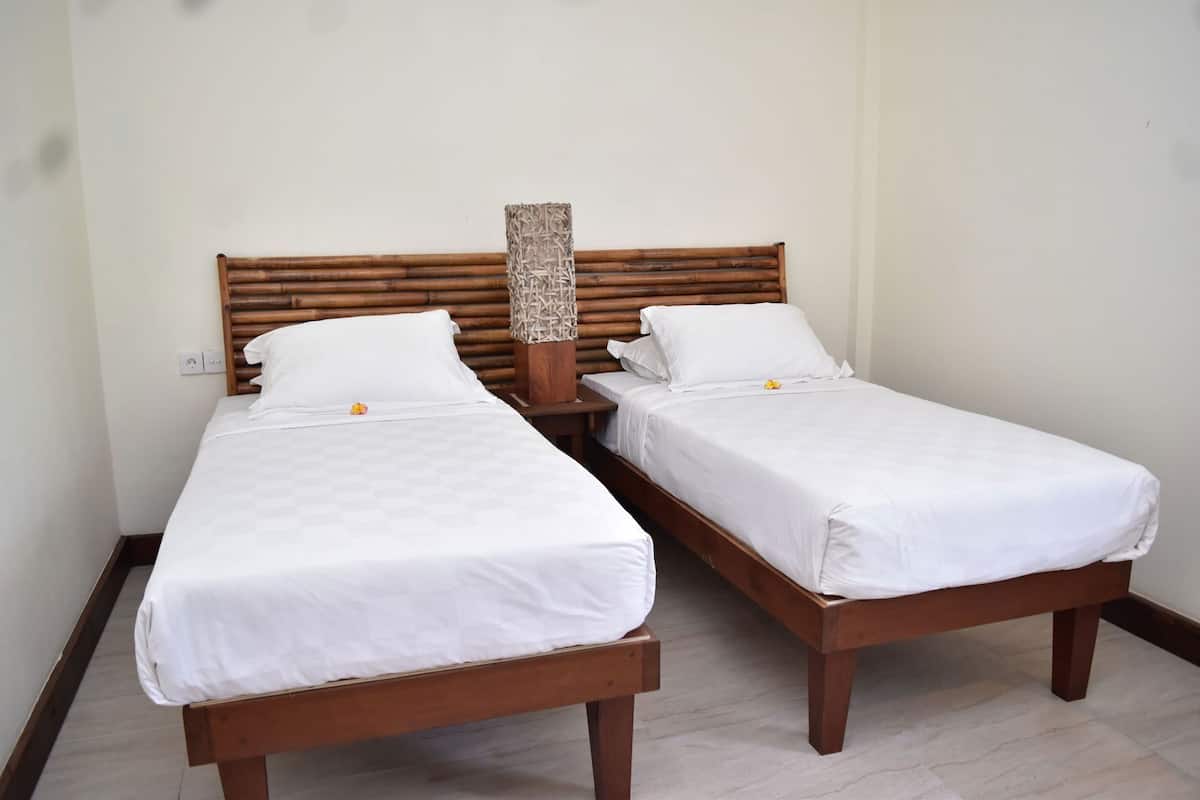 Una cama doble con cabecera de madera y mesita de noche con lámpara de mimbre.