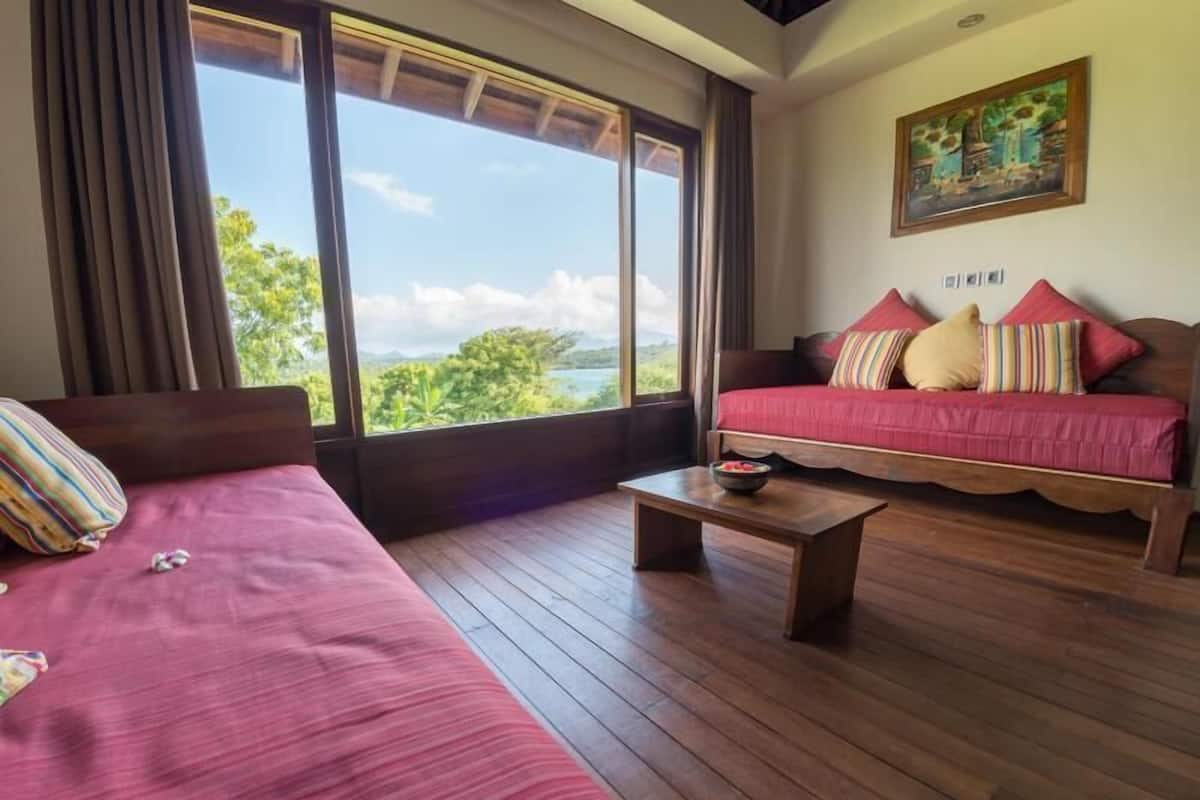 Una habitación con cama, sofá, una mesa de centro y un cuadro en la pared.