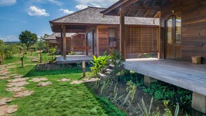 Una casa de madera con un porche cubierto, un jardín con piedras y una valla de madera.