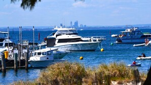 A marina with several boats docked, a city skyline in the background, and a clear blue sky. - Palms Bed & Breakfast (Warwick)