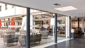 A modern outdoor seating area with wicker furniture and glass partitions. - New Hotel of Marseille (Marseille)