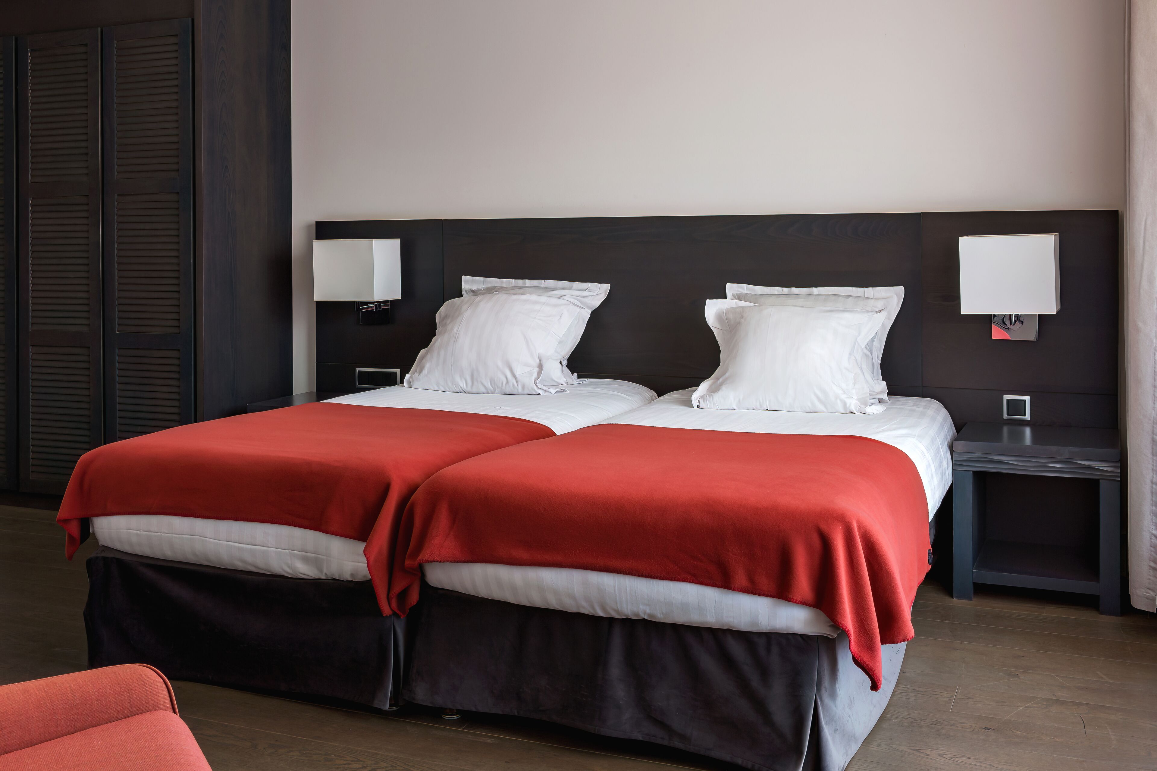 A double bed with red and white bedding, two bedside tables with lamps, and a dark wooden headboard.
