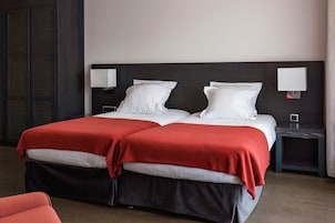 A double bed with red and white bedding, two bedside tables with lamps, and a dark wooden headboard.