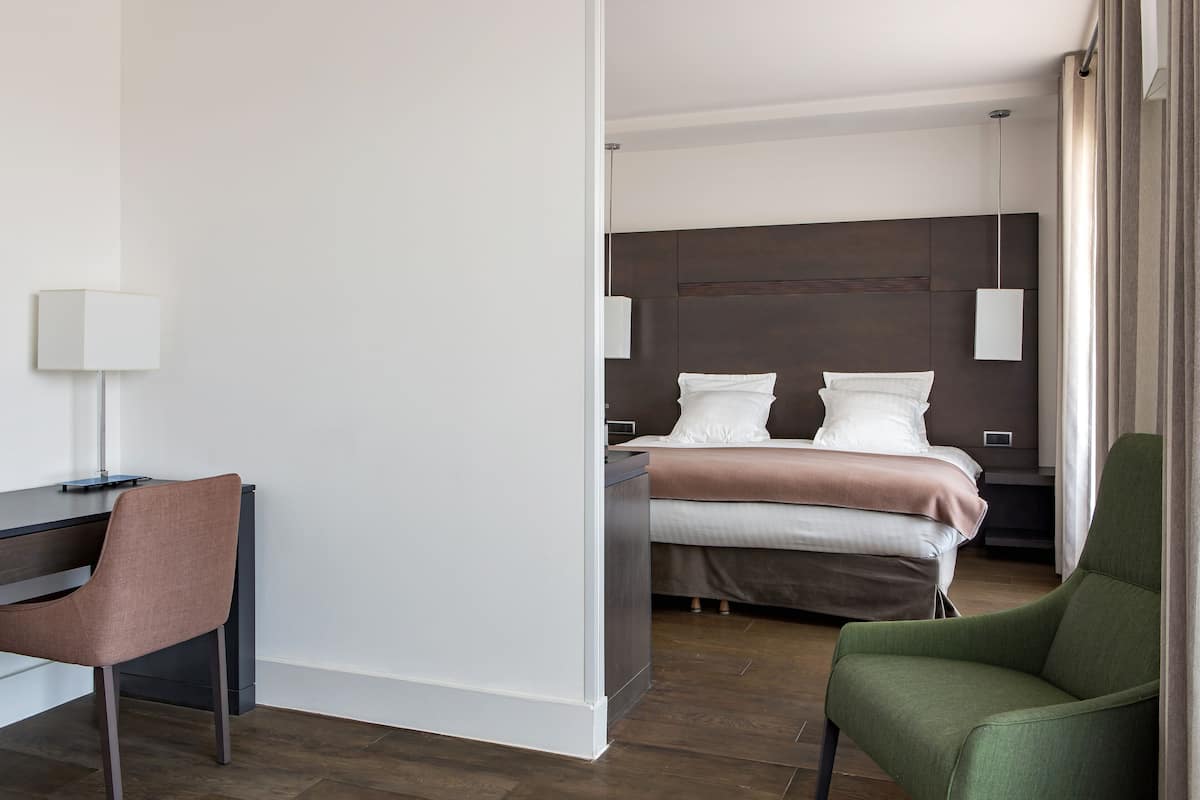 Hotellihuone, jossa on sänky, työpöytä, tuoli ja yöpöytä.