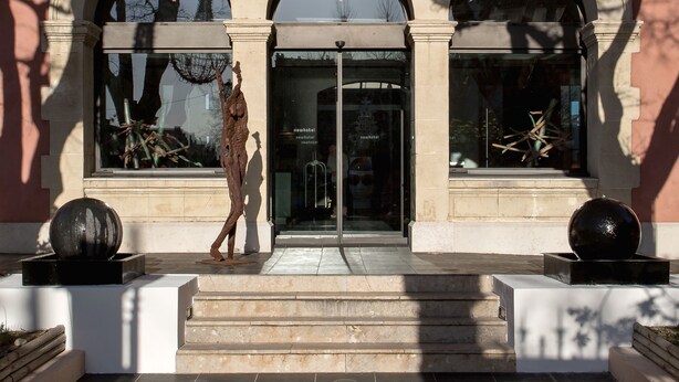 A building with a prominent arched entrance, a sign above the door, and a modern sculpture in front. - New Hotel of Marseille (Marseille)