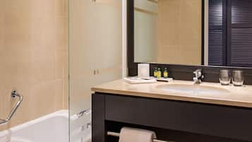 A modern bathroom with a glass shower enclosure, a bathtub, a vanity with a mirror, and a towel rack.
