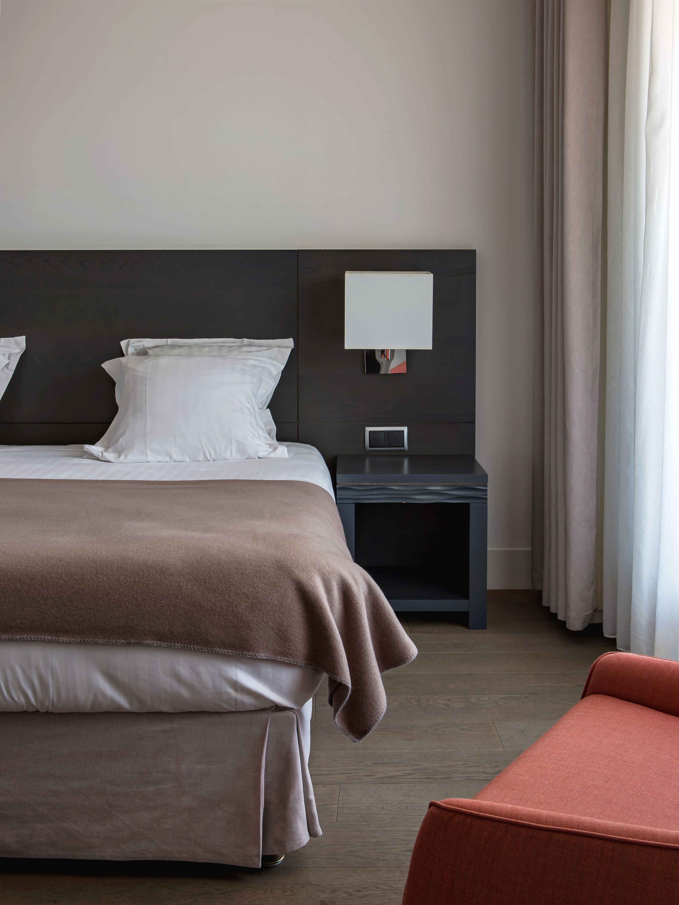 A hotel room with a large bed, a bedside table with a lamp, and a chair.