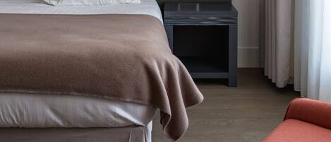 A hotel room with a large bed, a bedside table with a lamp, and a chair.