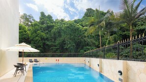 A swimming pool with a tiled deck, lounge chairs, and an umbrella. - Inn Hotel Macau  (Taipa)