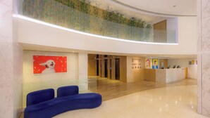 A modern hotel lobby with a reception desk, seating area, and a glass railing overlooking the lobby. - Inn Hotel Macau  (Taipa)