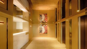 A modern hotel corridor with wooden floors, a reception desk, and a colorful abstract wall art. - Inn Hotel Macau  (Taipa)