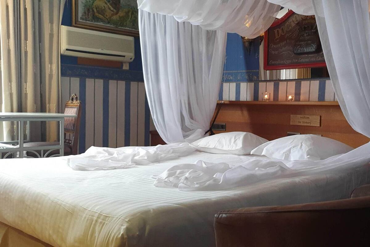 A hotel room with a bed, a bedside table, and a chair.