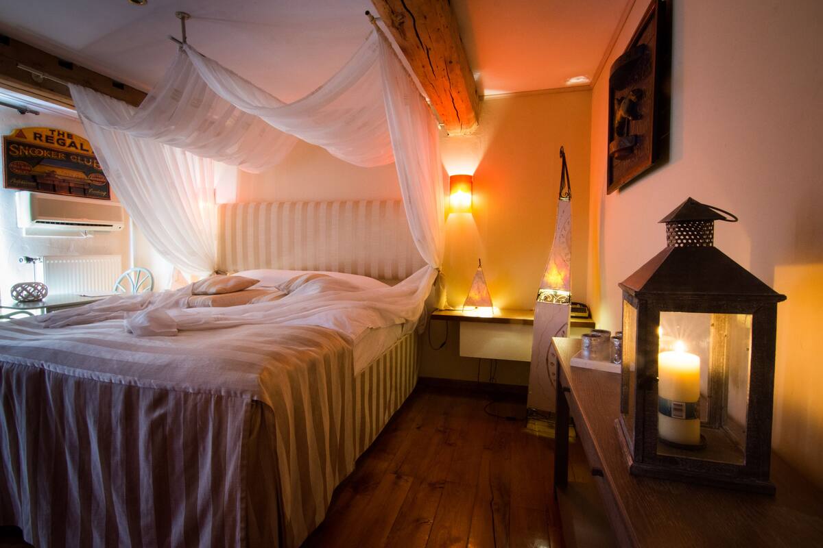 A bedroom with a bed, a nightstand, a wall-mounted lamp, and a lantern.