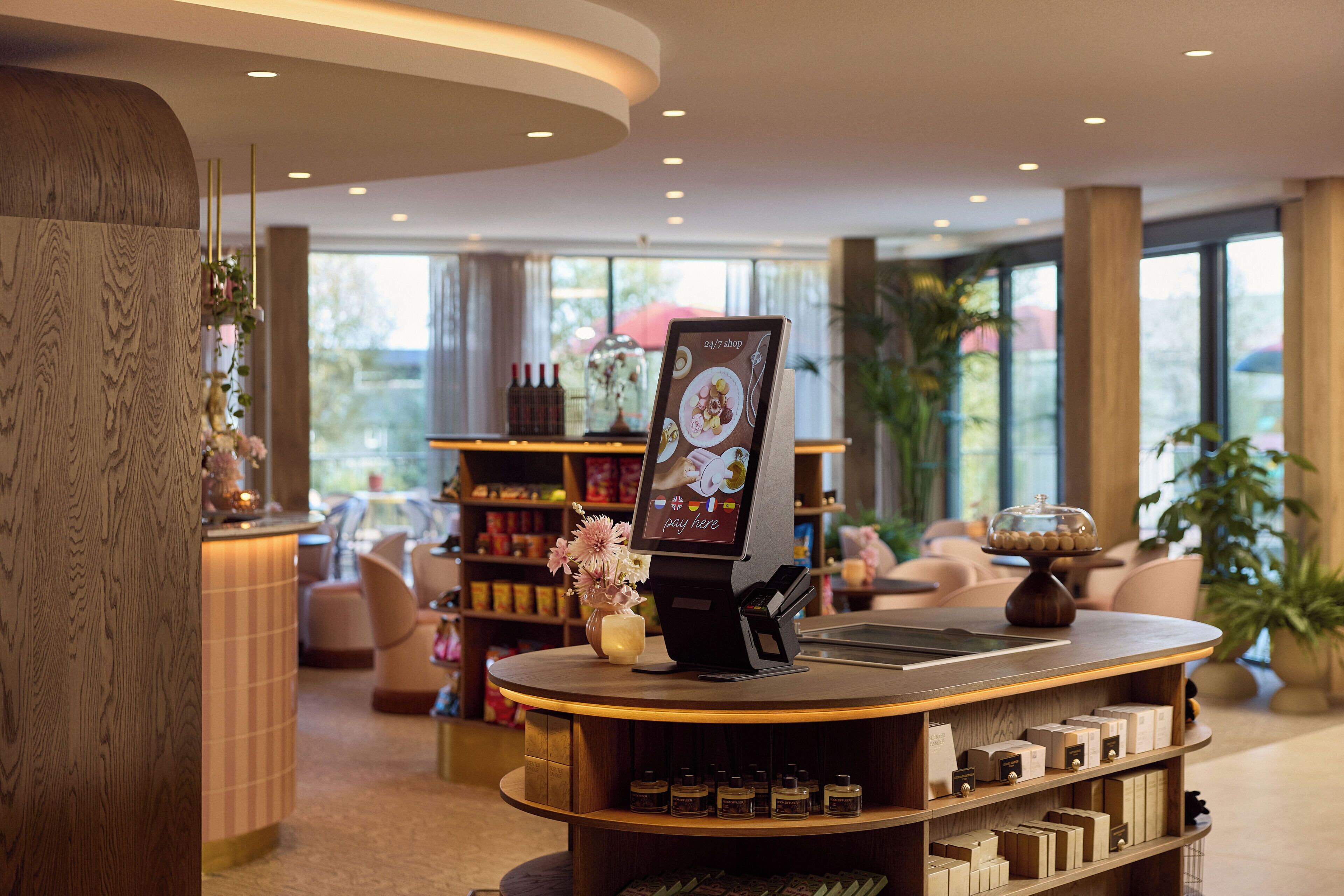 A reception area with a digital kiosk, a display of scented candles, and a seating area with a view of the outdoors.