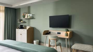 Ein modernes Hotelzimmer mit einem Bett, einem Schreibtisch mit Stuhl, einem Fernseher und einer kleinen Bank.