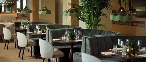 Un restaurant doté de plusieurs cabines, chacune comprenant une table, des chaises et une petite plante.