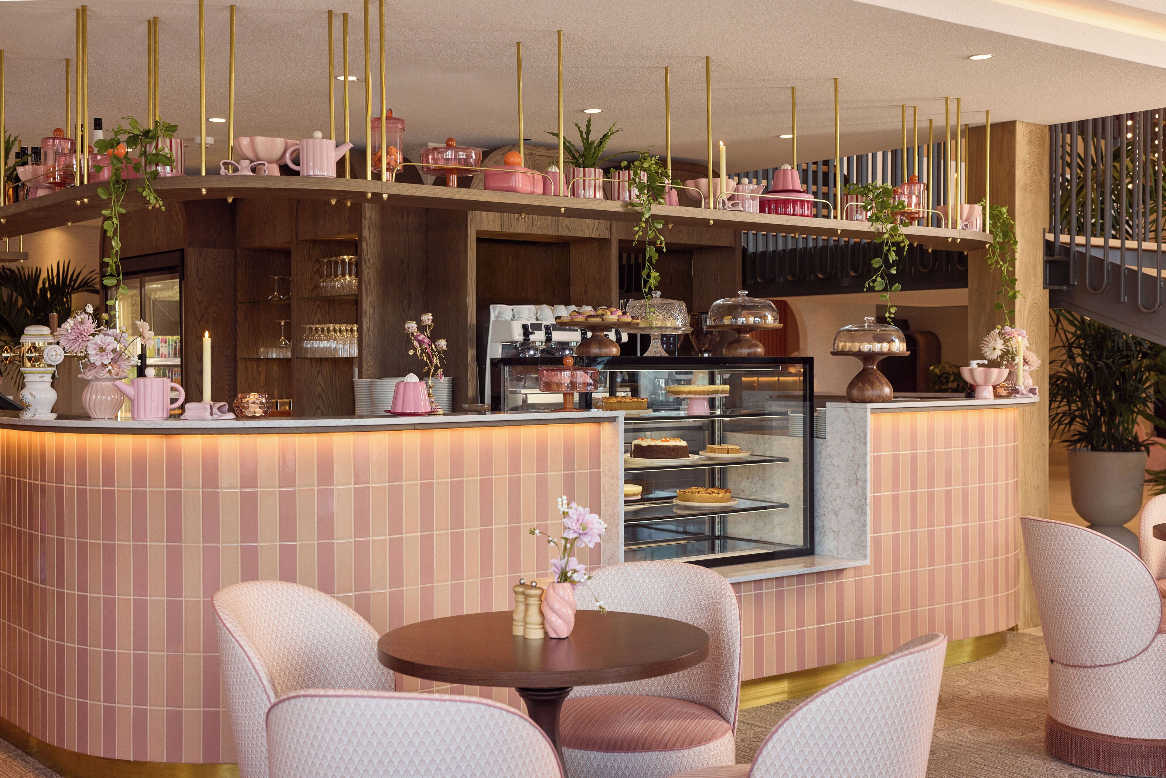 Un área de bar moderna con temática rosa, con asientos y una vitrina.