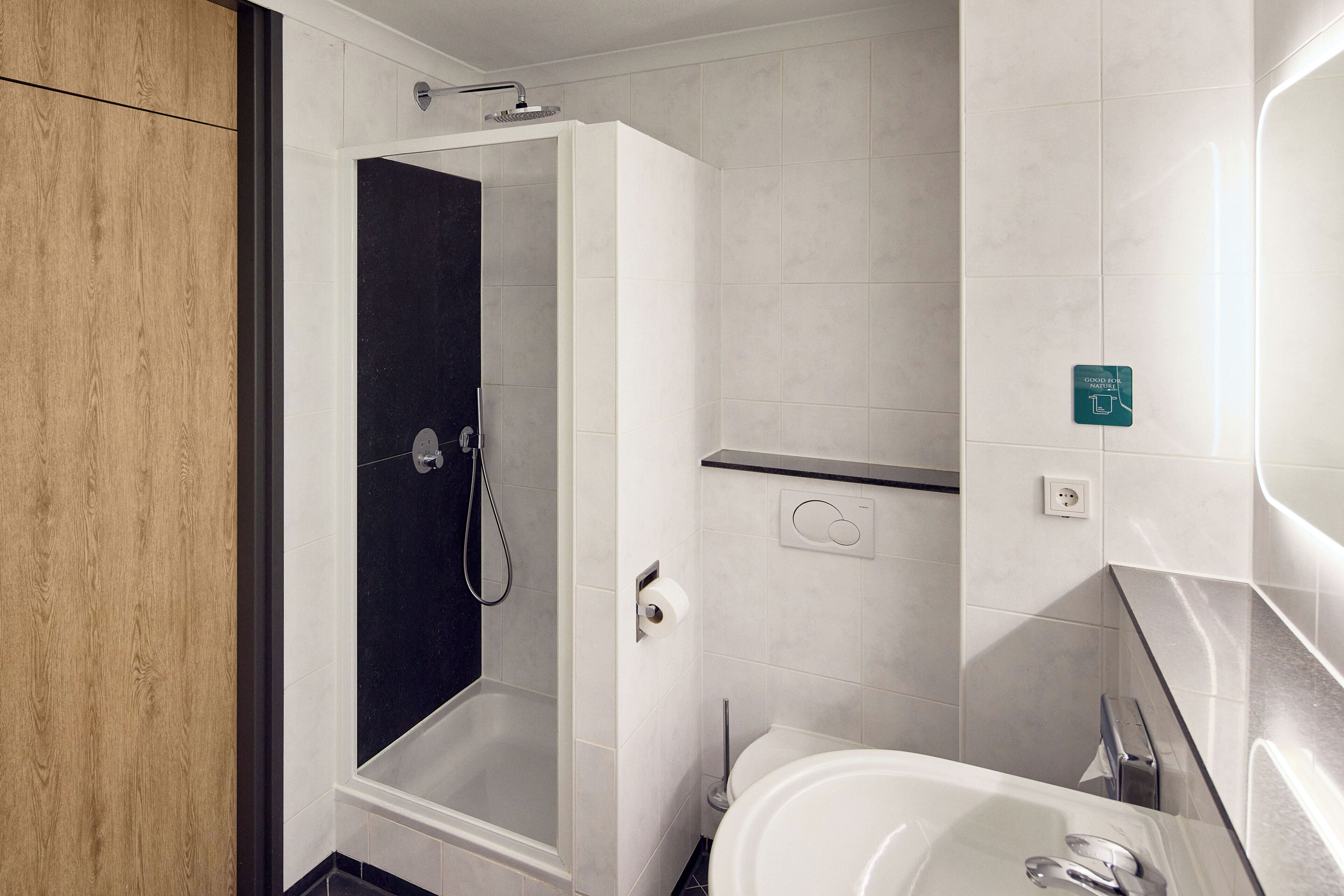 Un baño moderno con ducha acristalada, una bañera blanca y un inodoro.