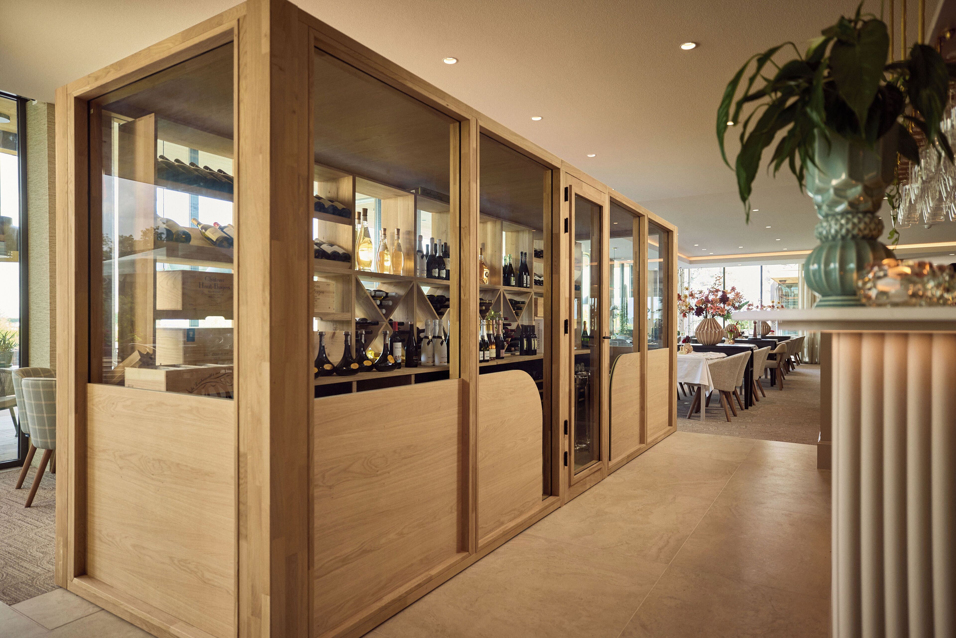 Un espace bar moderne agrémenté de cloisons en bois, d’étagères à bouteilles et d’un coin repas avec des tables et des chaises.