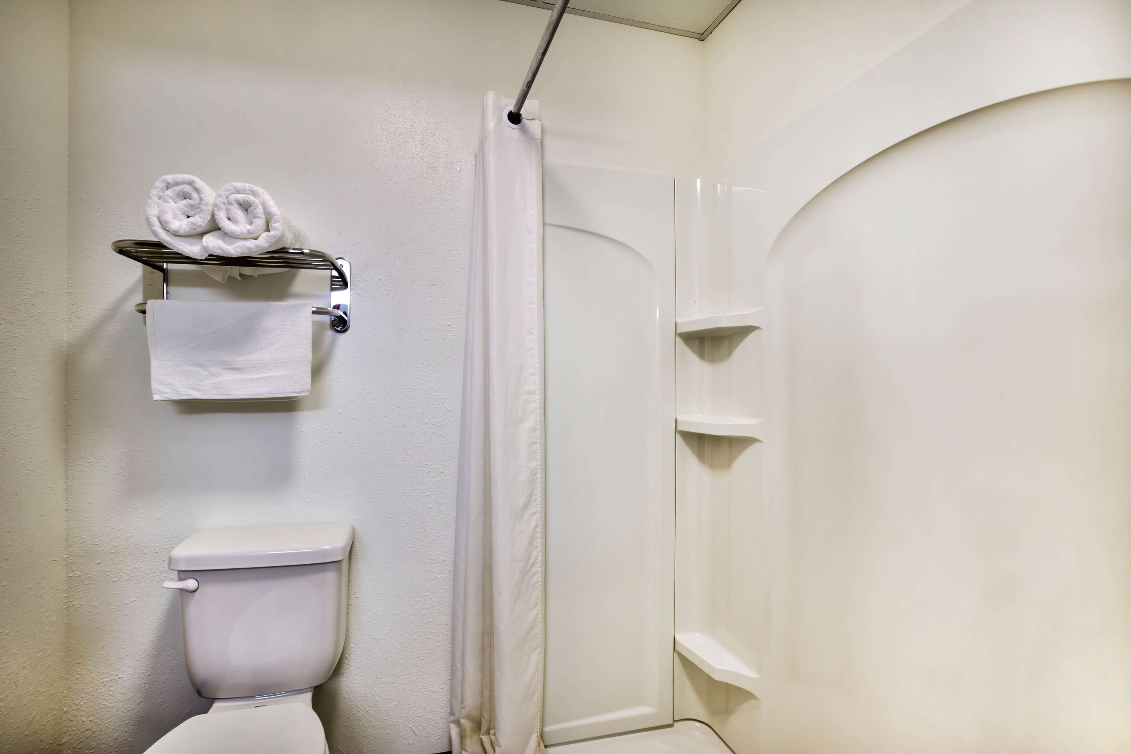 A bathroom with a toilet, a towel rack with towels, and a shower area.