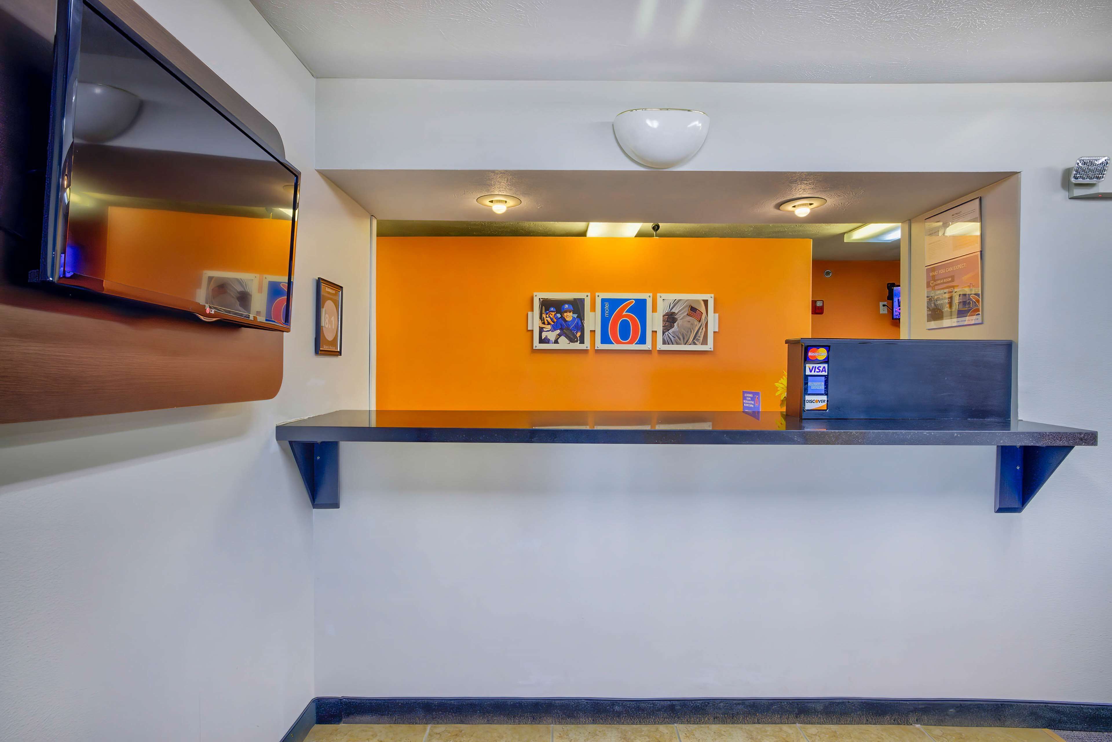 Un área de recepción con mostrador, cuadros en la pared y una lámpara en el techo.