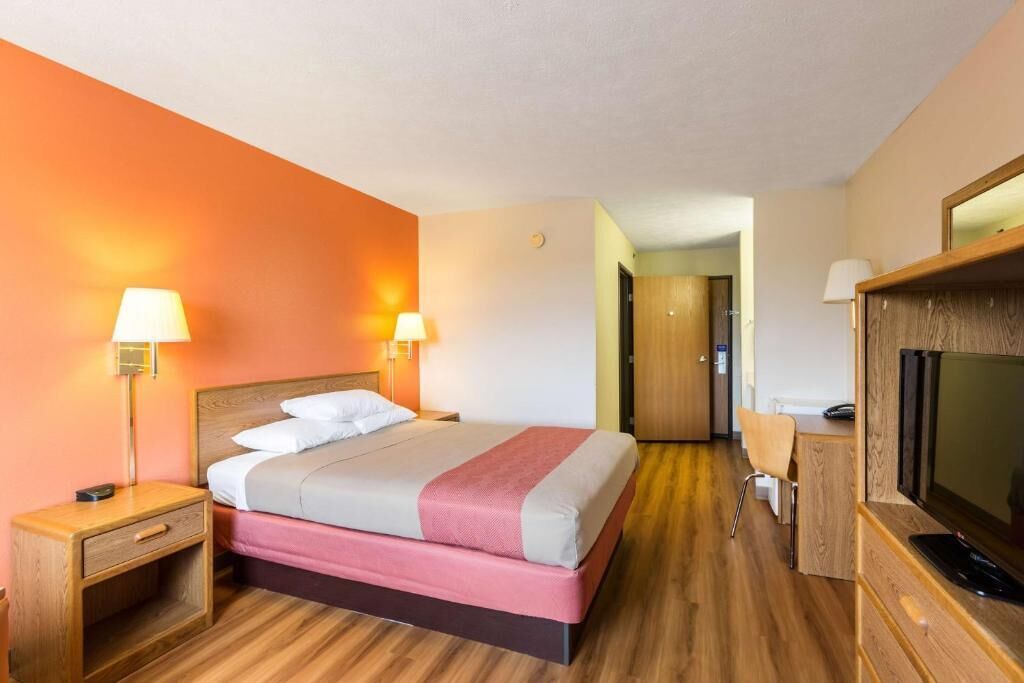 Une chambre d’hôtel avec un lit, des lampes de chevet, une télévision et un bureau.
