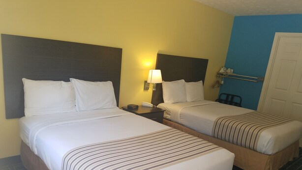 A hotel room with two beds, each with a headboard, a bedside table with a lamp, and a phone. - Meriwether Country Inn (Warm Springs)