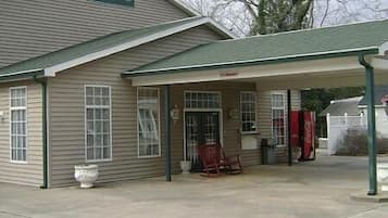A two-story building with a sign reading "Pinehurst Country Inn." There is a covered porch with a rocking chair and a Coca-Cola cooler.