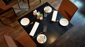 Un tavolo da pranzo apparecchiato con piatti, posate e condimenti, circondato da sedie.