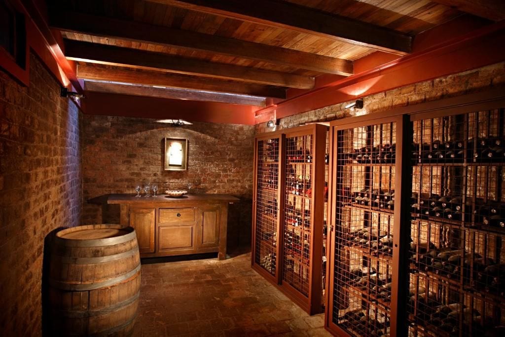 Una celler de vi amb tones de fusta, barrils, una prestatgeria i un taulell de fusta.