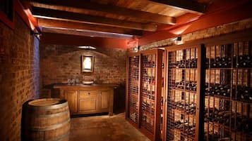 Una celler de vi amb tones de fusta, barrils, una prestatgeria i un taulell de fusta.