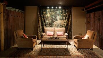 Una habitación acogedora con un sofá y dos sillones, un tapiz estampado y techo de madera.