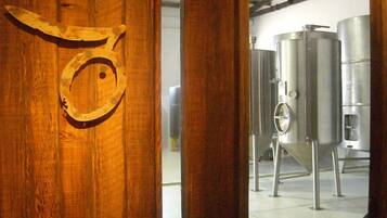 Una puerta de madera con un emblema de cabeza de animal de metal, que da a un cuarto con tanques de acero inoxidable.
