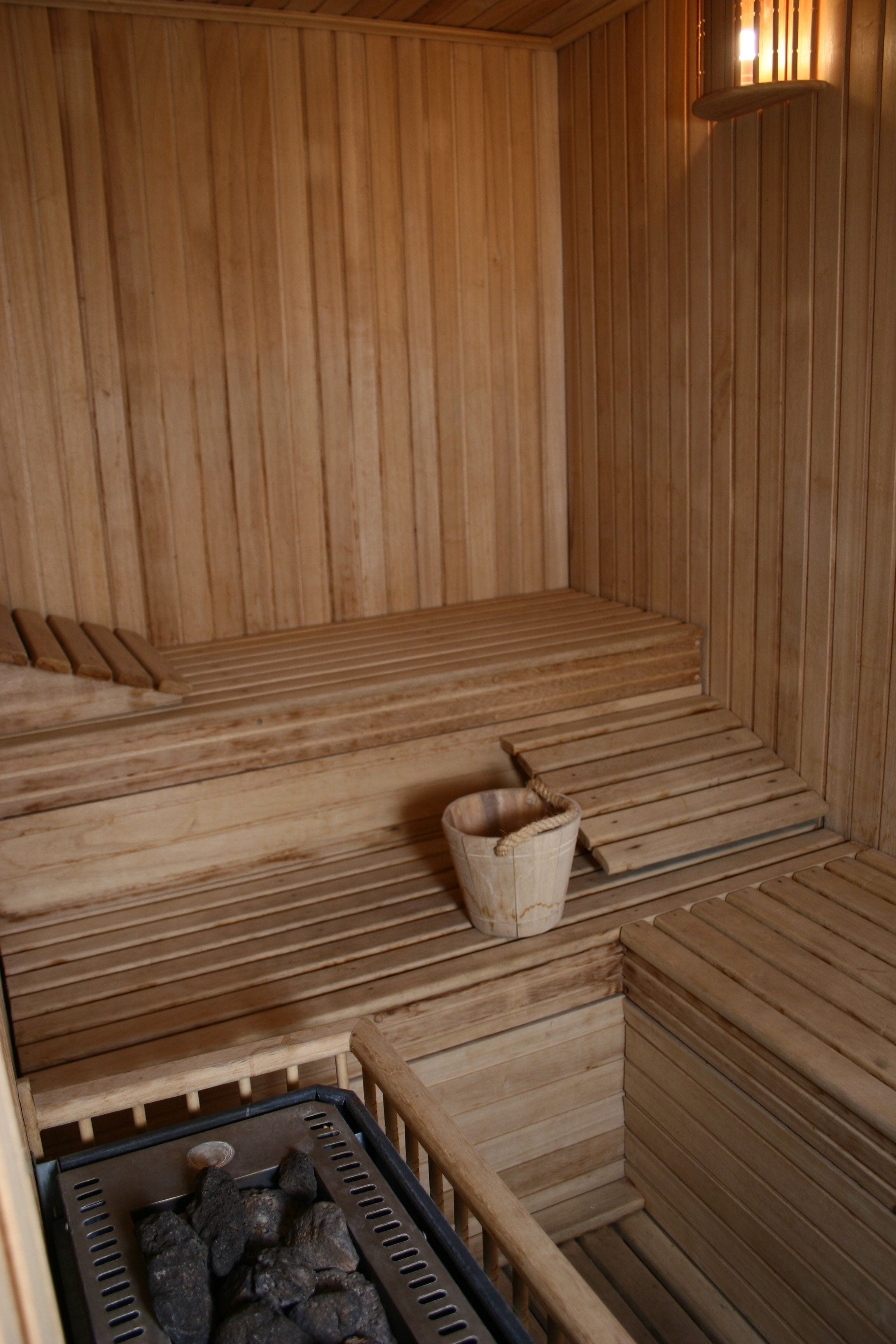 A wooden sauna with benches and a bucket.