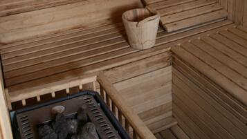 A wooden sauna with benches and a bucket.