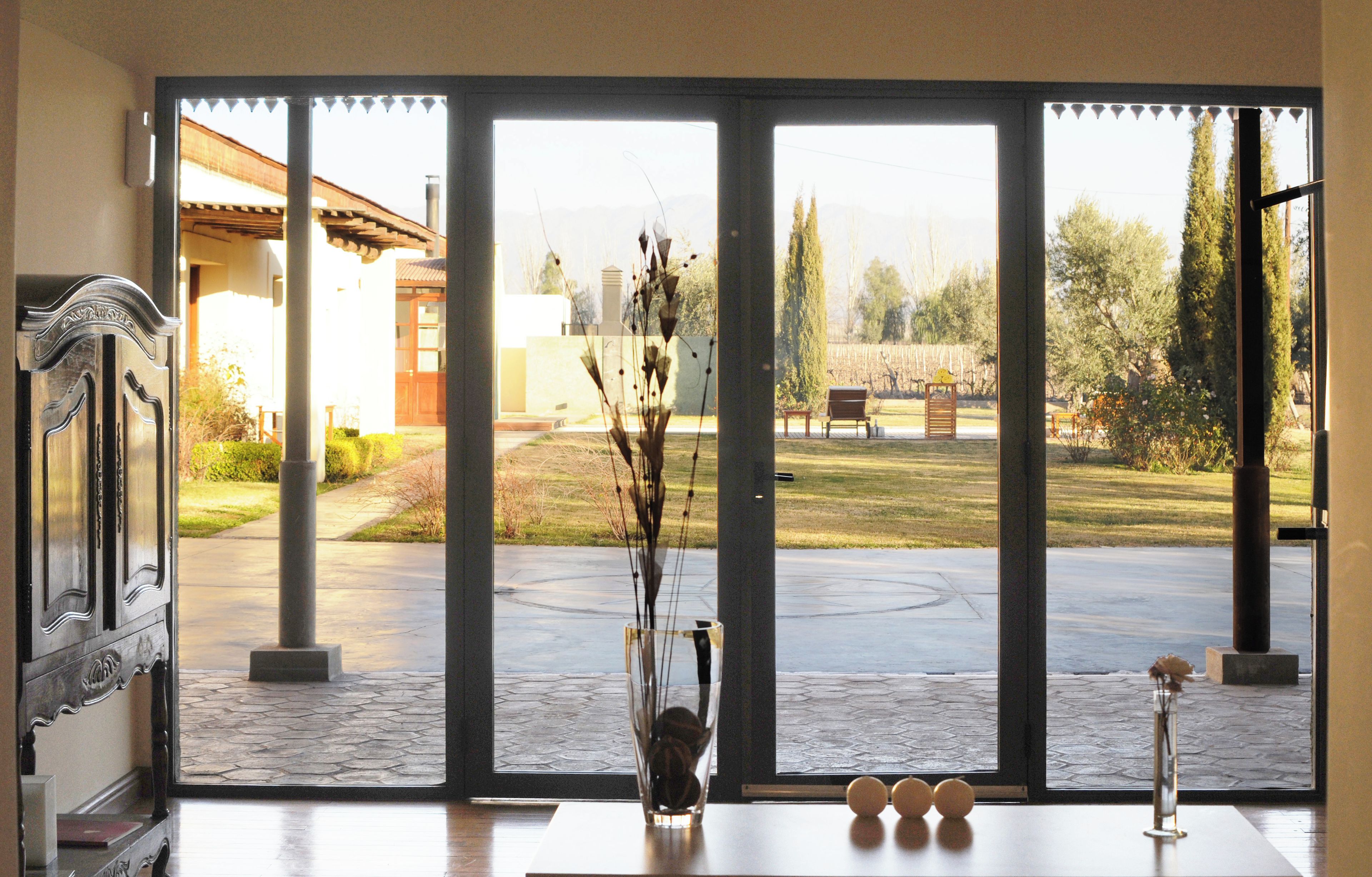 A room with a large sliding glass door leading to an outdoor area with a patio, a bench, and a garden.