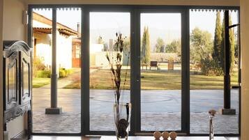 A room with a large sliding glass door leading to an outdoor area with a patio, a bench, and a garden.
