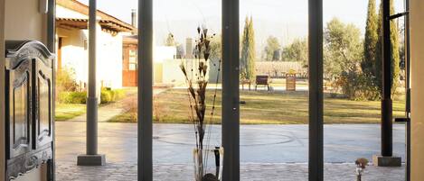 A room with a large sliding glass door leading to an outdoor area with a patio, a bench, and a garden.