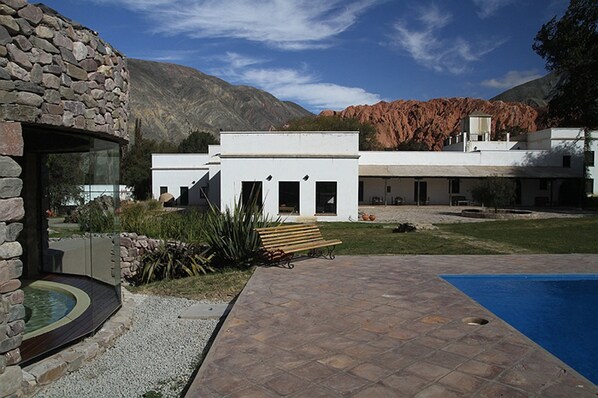 Un edificio moderno con fachada de piedra, piscina y un patio con banco.