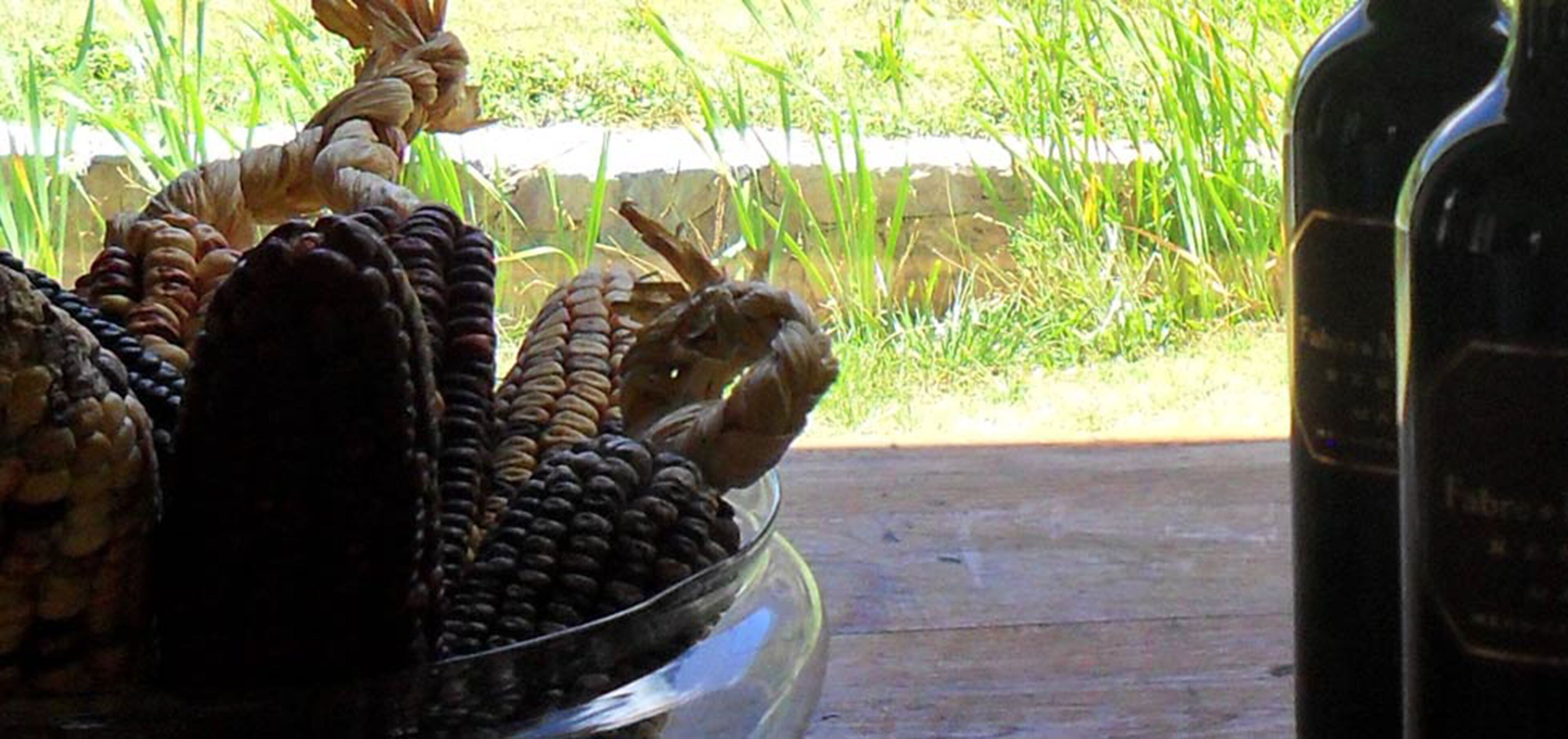 Un saladier en verre rempli d’épis de maïs, posé sur une surface en bois.