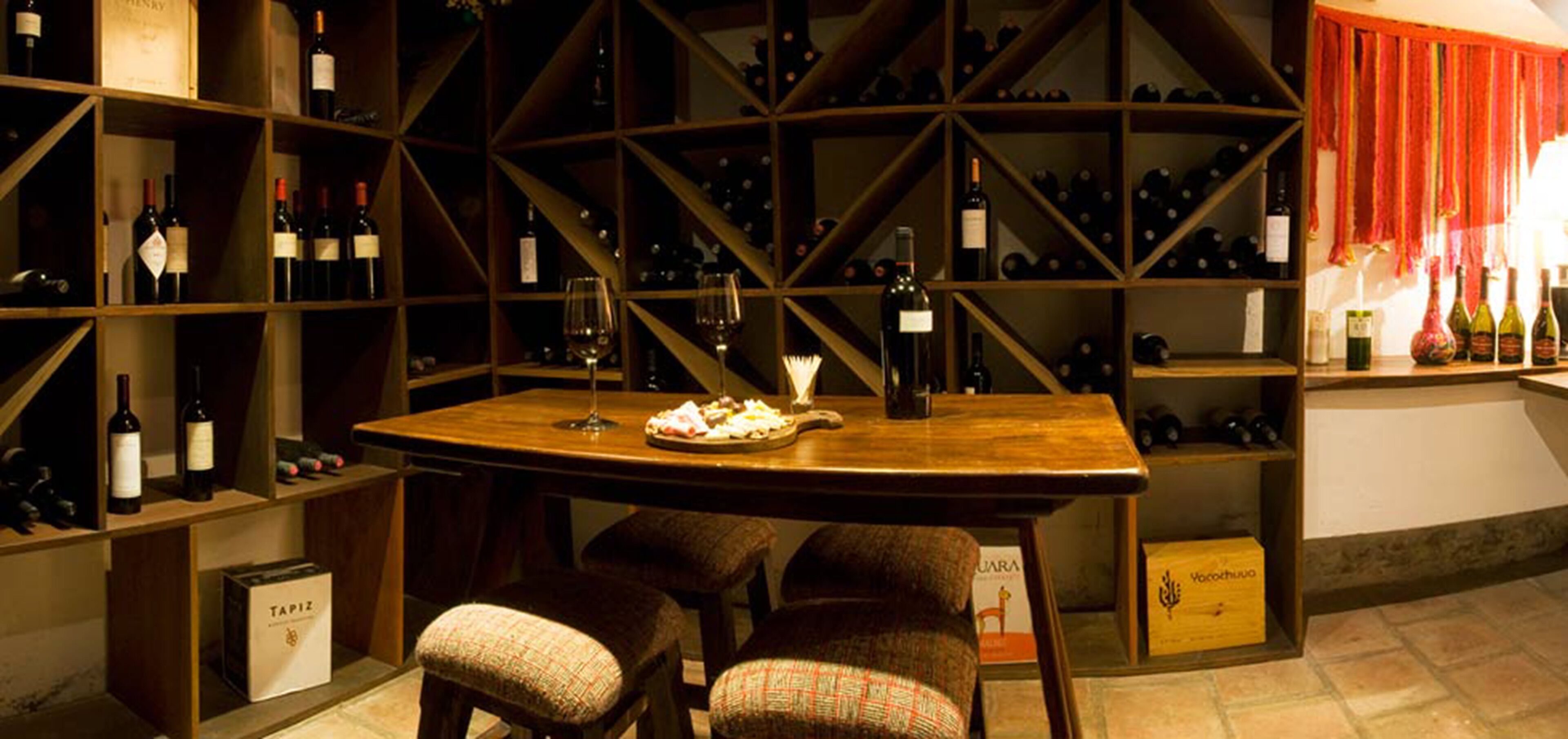 A wine cellar with wooden shelves and a table with two chairs.
