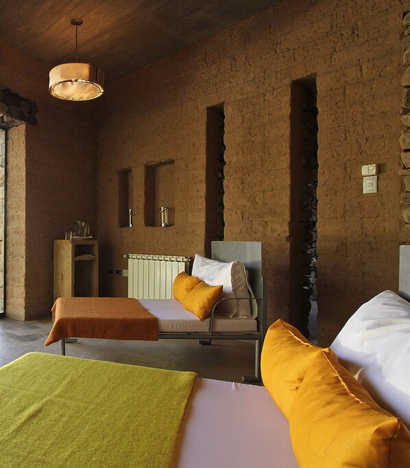 Quarto com cama, mesa de cabeceira de madeira, radiador e luminária suspensa.