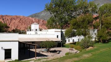 Un edificio blanco con techo plano y un espacio al aire libre cubierto, con un pequeño árbol.