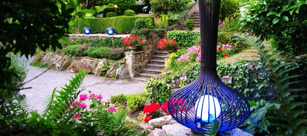 A garden with a stone staircase, lush greenery, and a blue spherical light fixture. - Le Manoir de Kertalg (Moelan-sur-Mer)