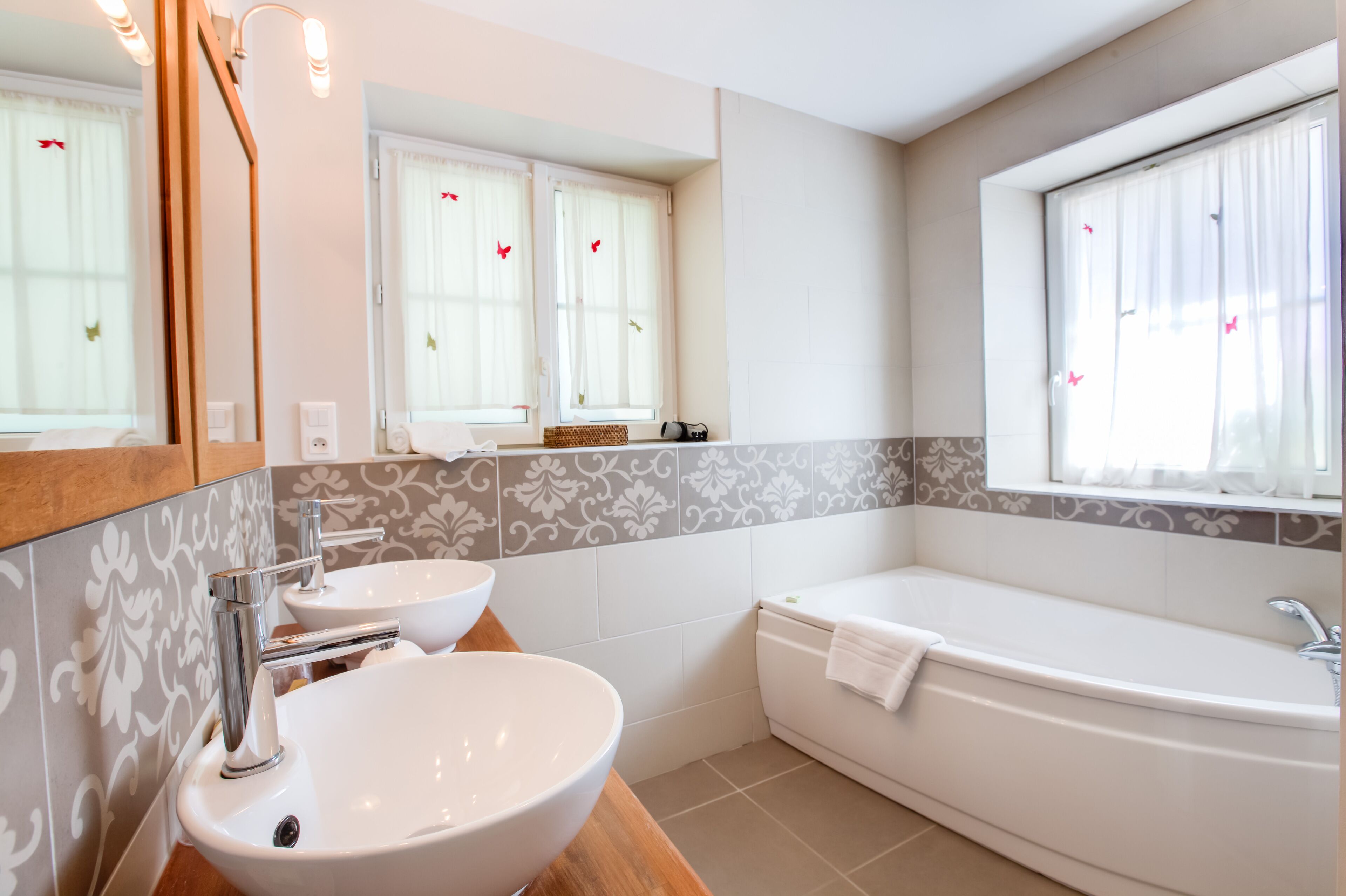 Ein modernes Badezimmer mit zwei Waschbecken, einer Badewanne und einem großen Spiegel.