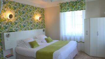 A bedroom with a bed, a wardrobe, and a wall with leaf-pattern wallpaper.